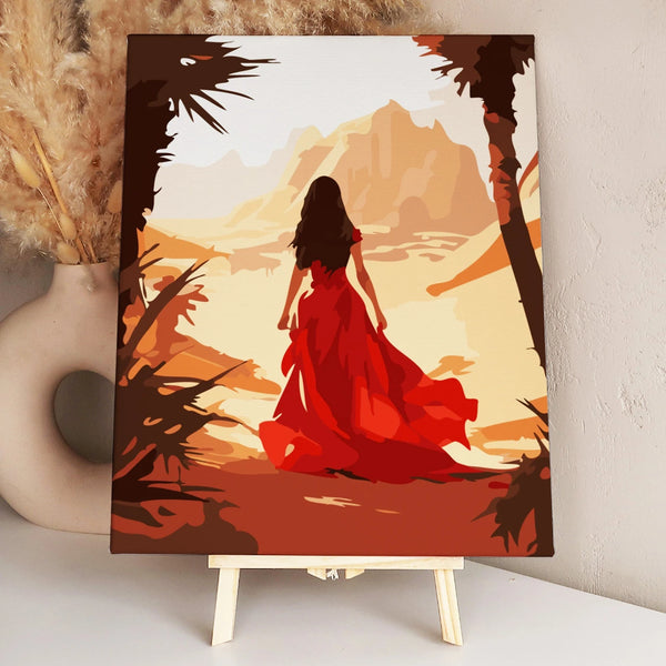 Woman in flowing red dress walking through a desert landscape