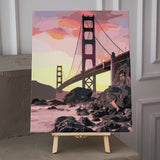 Golden Gate Bridge painting with sunset sky and rocky shoreline