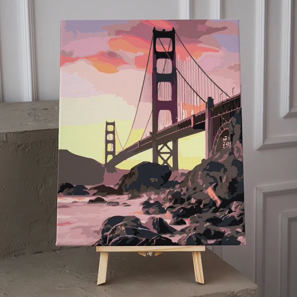 Golden Gate Bridge painting with sunset sky and rocky shoreline