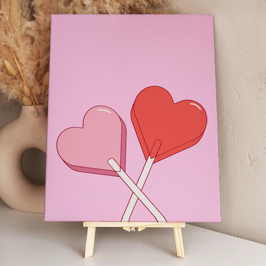 Two heart-shaped lollipops crossed against a pink background.