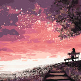 Silhouetted woman on a bench watching a dreamy pink sunset
