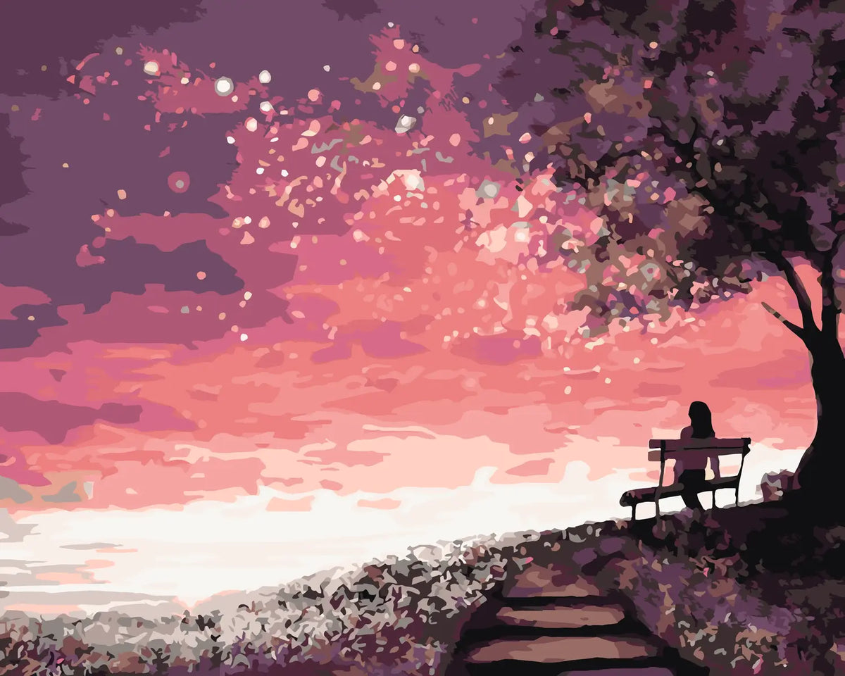 Silhouetted woman on a bench watching a dreamy pink sunset