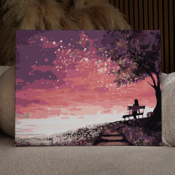 Silhouetted woman on a bench watching a dreamy pink sunset