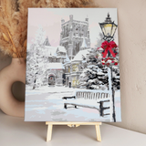 Snowy winter scene with castle, festive lamp post, and bench painting