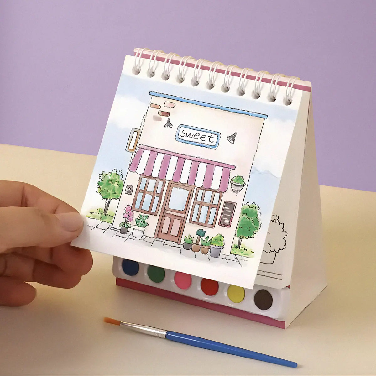 Compact travel art kit with watercolor paints, brush, and spiral pad