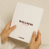 White wellness journal held in hands with pink and brown lettering
