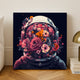 Flowernaut paint by numbers finished canvas, an astronaut helmet full of pink and orange flowers, standing on a wooden floor by a white wall