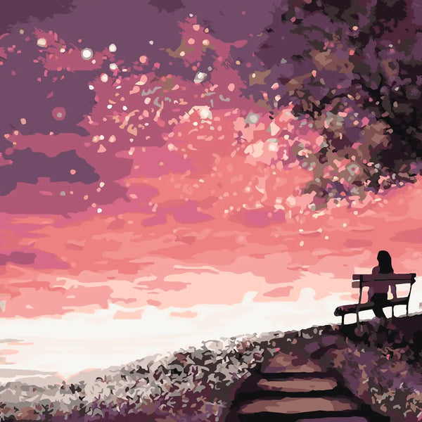 Silhouetted woman on a bench watching a dreamy pink sunset