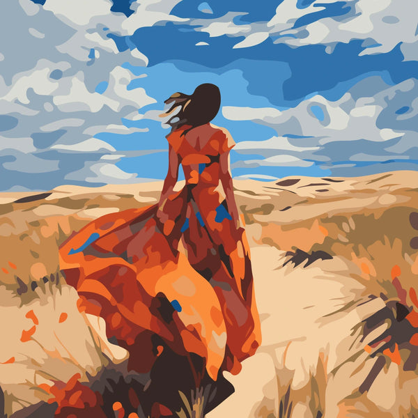 Woman in flowing red dress walking through a desert landscape